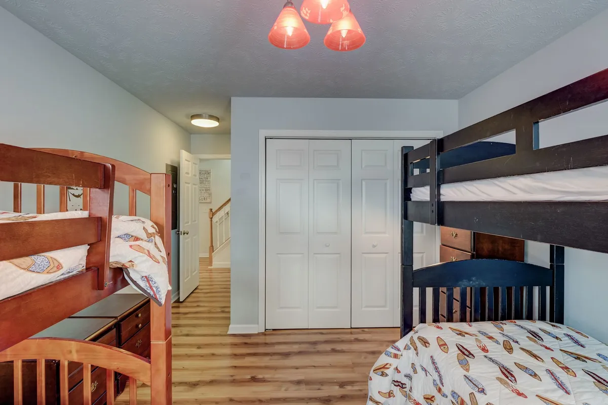 A cozy bunk bed setup with playful lighting and a storage dresser, creating a fun and inviting atmosphere for children or young guests. The space speaks to sleepovers, late-night talks, and shared laughter.