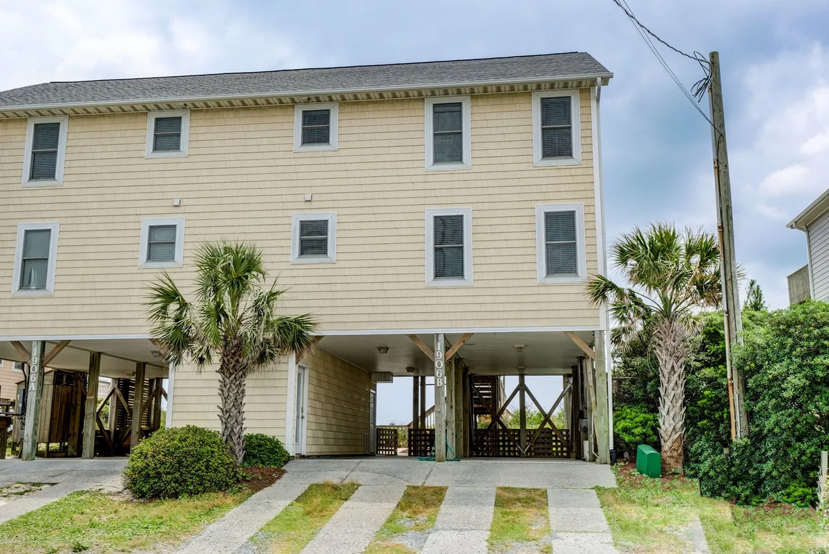 An exterior view of the house highlights the surrounding palm trees and the shaded area beneath the home. There's ample grassy space, ideal for outdoor games, lounging, and safe play for children and pets. The relaxed setting conveys a sense of leisure and comfort.